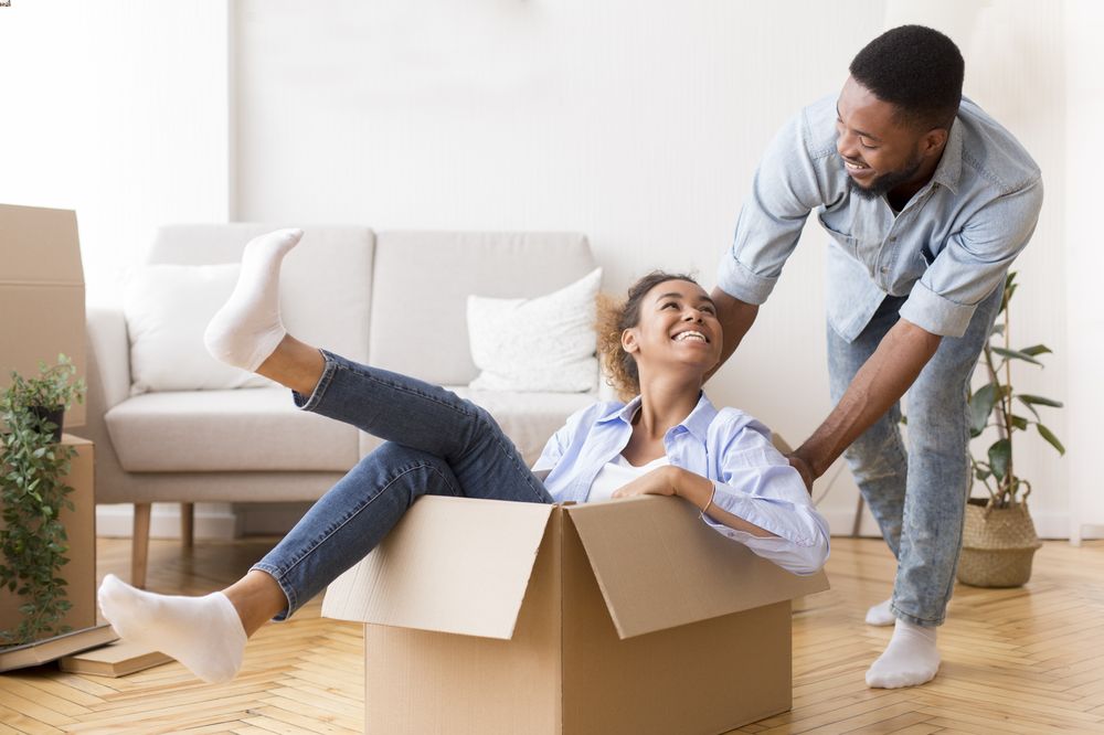 Woman in a cardboard box being pushed by a man preventing break in with home security system