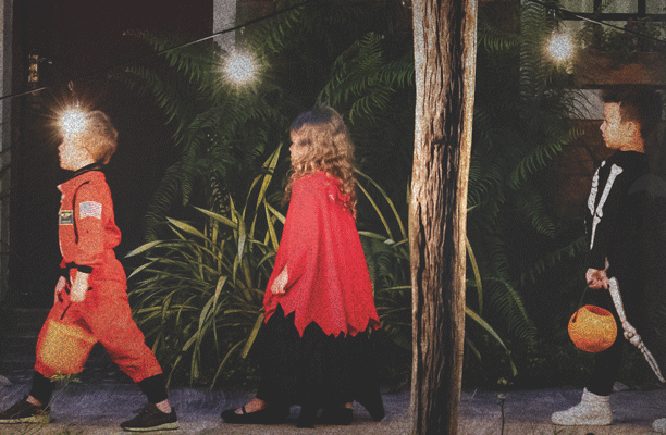 Kids in their Halloween costumes trick-or-treating at night in their neighborhood