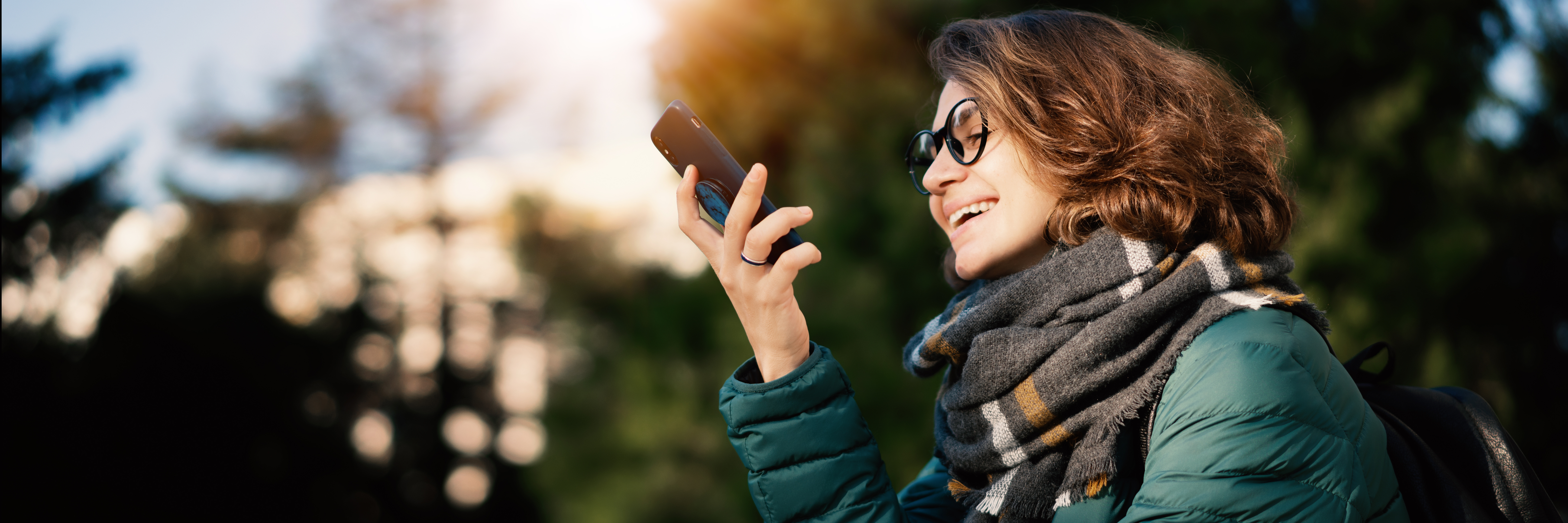 Young woman with the Myemailnotifier mobile app, where she can arm her security system, watch live or recorded camera footage, adjust your smart thermostat, and more.